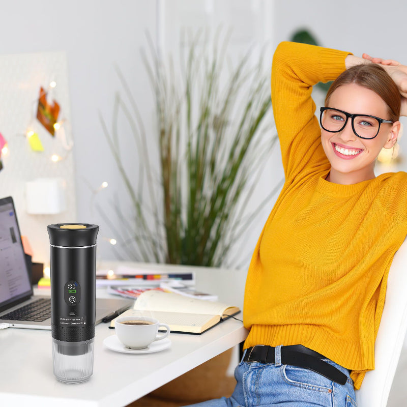 Woman in yellow sweater sitting at a desk with a coffee cup and black travel mug.