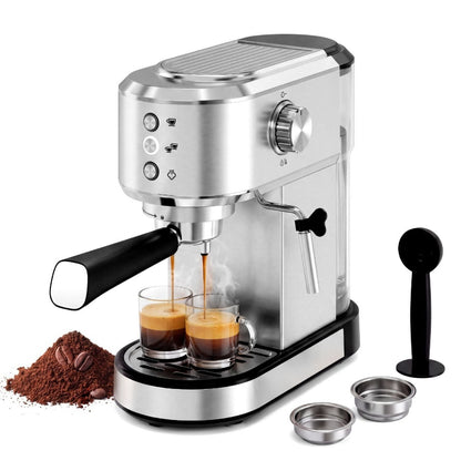A stainless steel semi-automatic espresso machine with a black handle and base, shown dispensing espresso into two glass cups. The machine is displayed on a clean white background with accessories including a scoop, two metal filter baskets, and a pile of coffee beans and ground coffee.