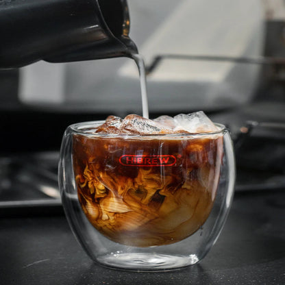 Iced coffee being poured into a glass with a brand logo, blurred background