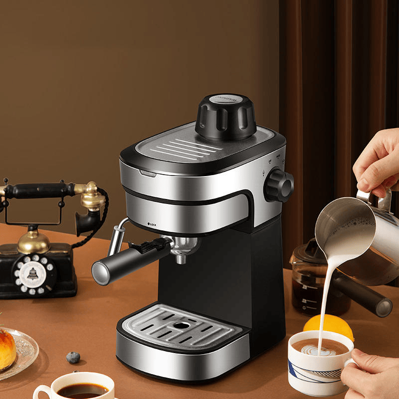 Espresso machine on a table with a person pouring milk into a cup, an old-fashioned phone, and a jar in the background.